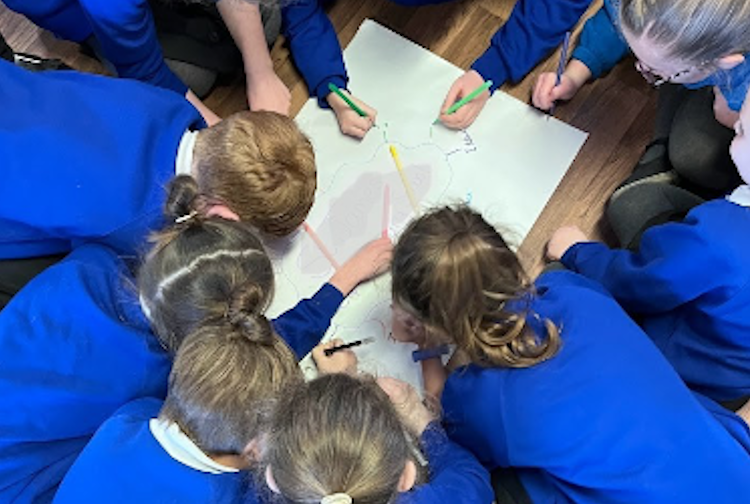 Schoolchildren crowded around a piece of paper.