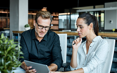 Photo of two office workers looking at a tablet