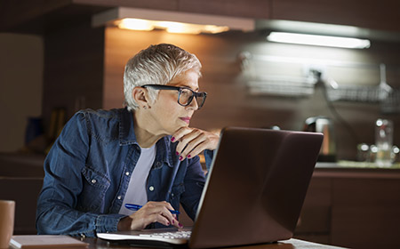 A person working on a laptop in a dimly lit room