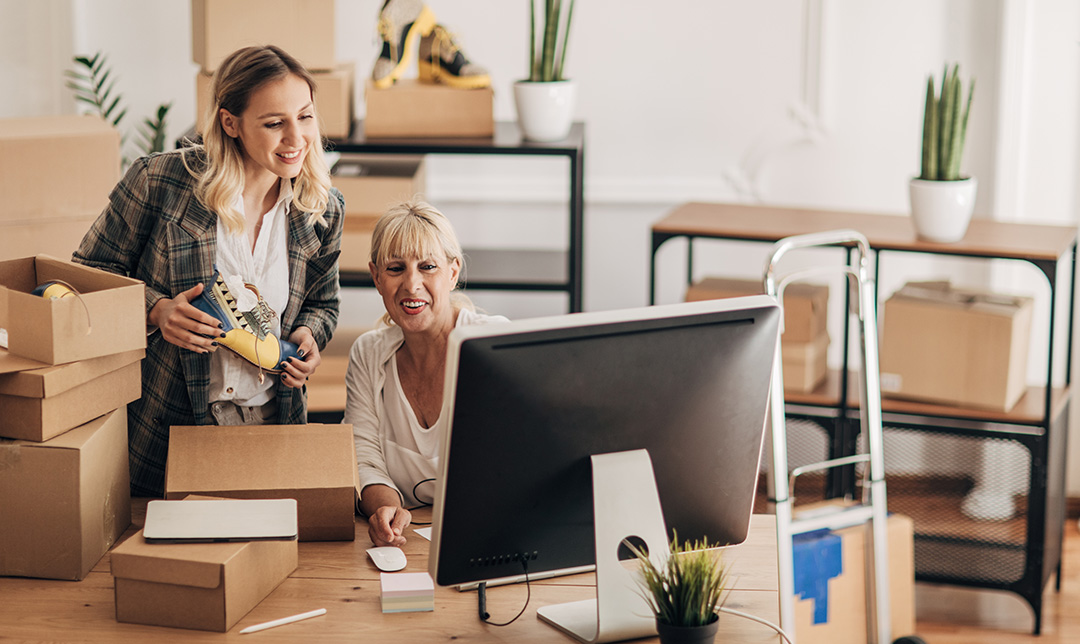 Two business workers are reviewing information on a computer, signifying Bankline's features, to create roles and delegate responsibilities to suit your business needs.