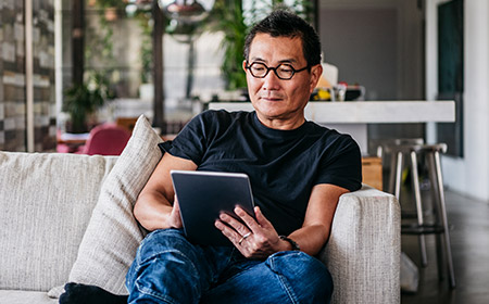 Person sitting on a sofa using a tablet indoors.