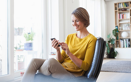 Person sitting indoors and smiling while using a smartphone