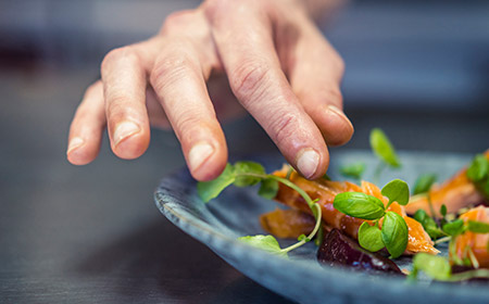 Photo of a hand about to pick up a piece of food from a bowl