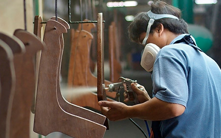 Photo of man wearing respirator and spraying furniture in factory