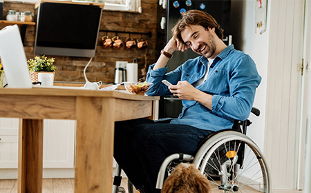 Photo of a man sitting in a wheelchair at a dining table