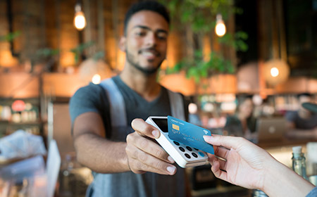 Photo of an aproned man holding out a device to take a card payment