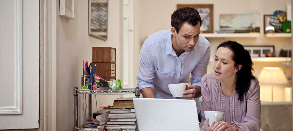 Woman looking at laptop holding her debit card
