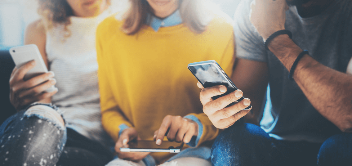 Close up group of adult friends sitting in a sofa with phones in hand