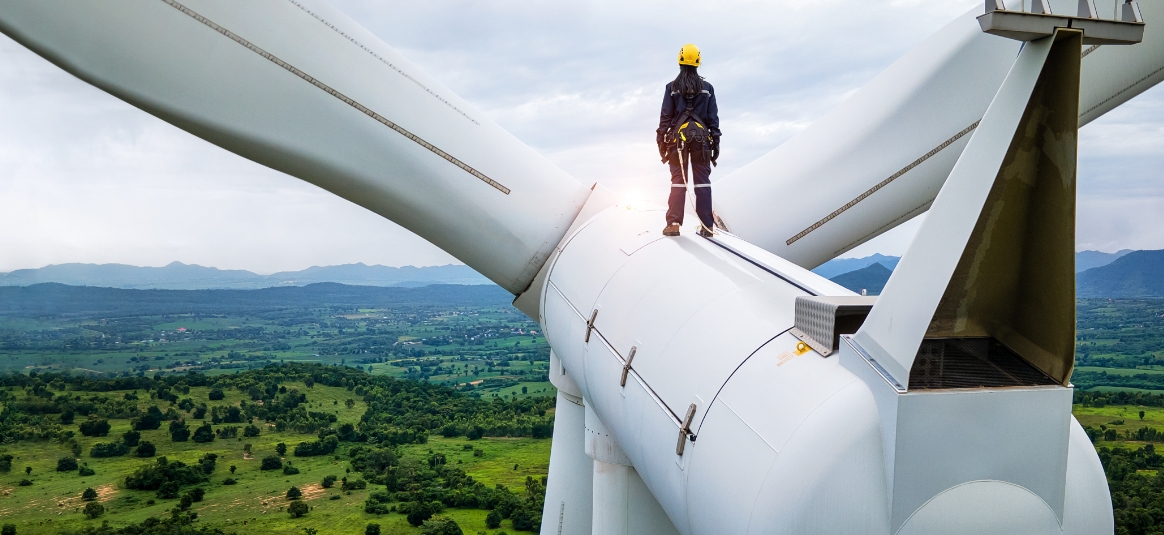 Female worker on top of a wind turbine looking out