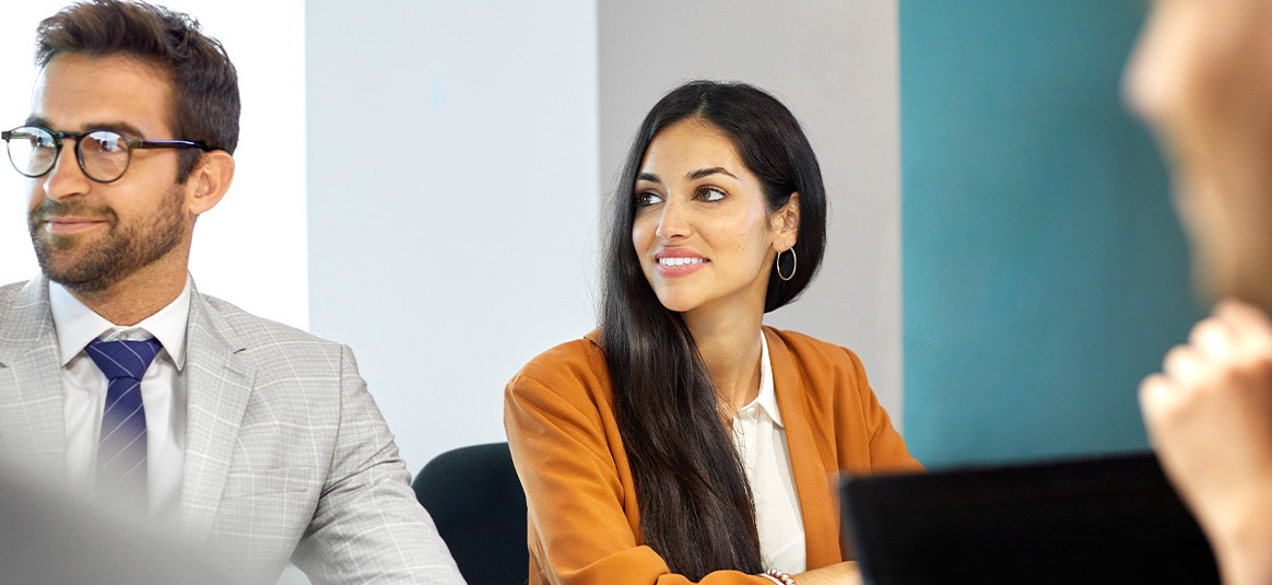 Photo of two smiling people wearing suits and looking to the left of the image.