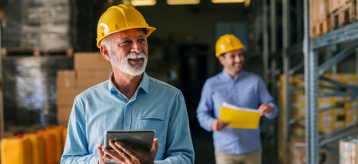 Two workers in a warehouse wearing hard hats