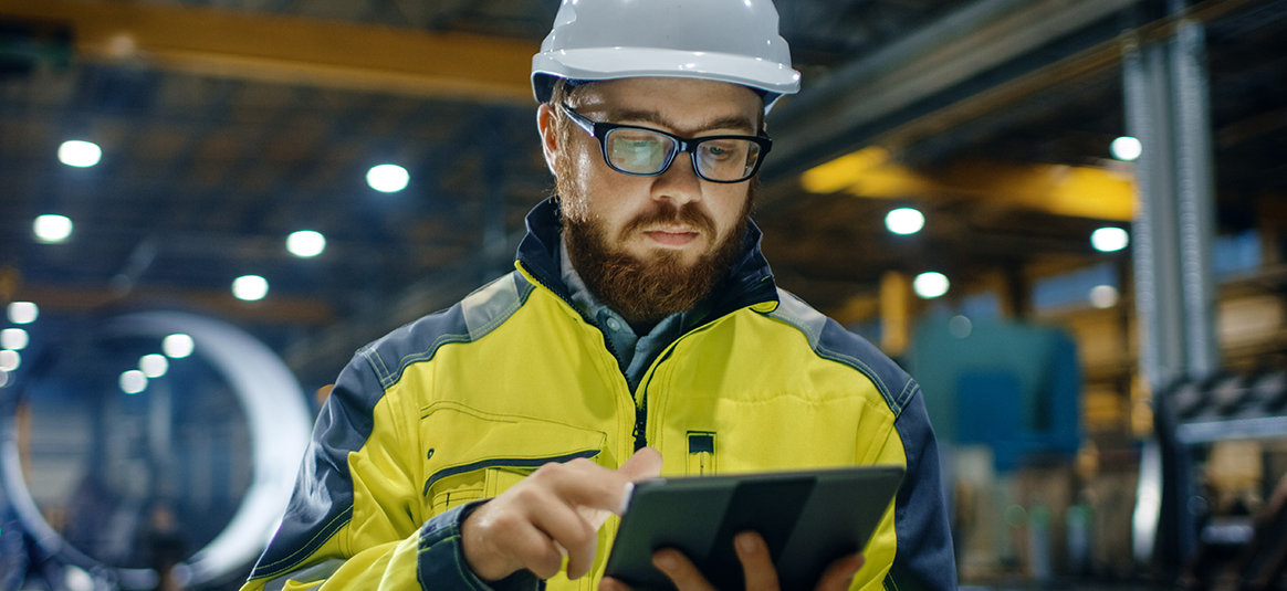 Worker in high visibility clothing using a tablet device
