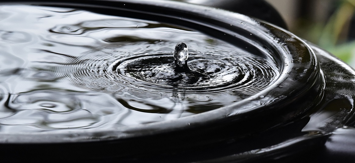 a water droplet, splashing into a pool and causing ripples