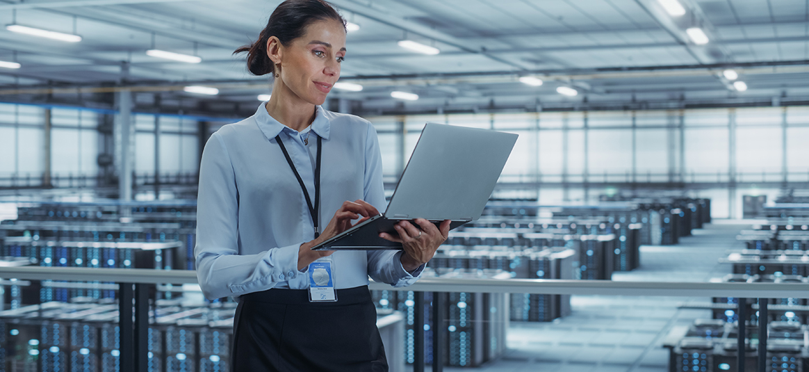 Picture of a woman holding a laptop in a data centre