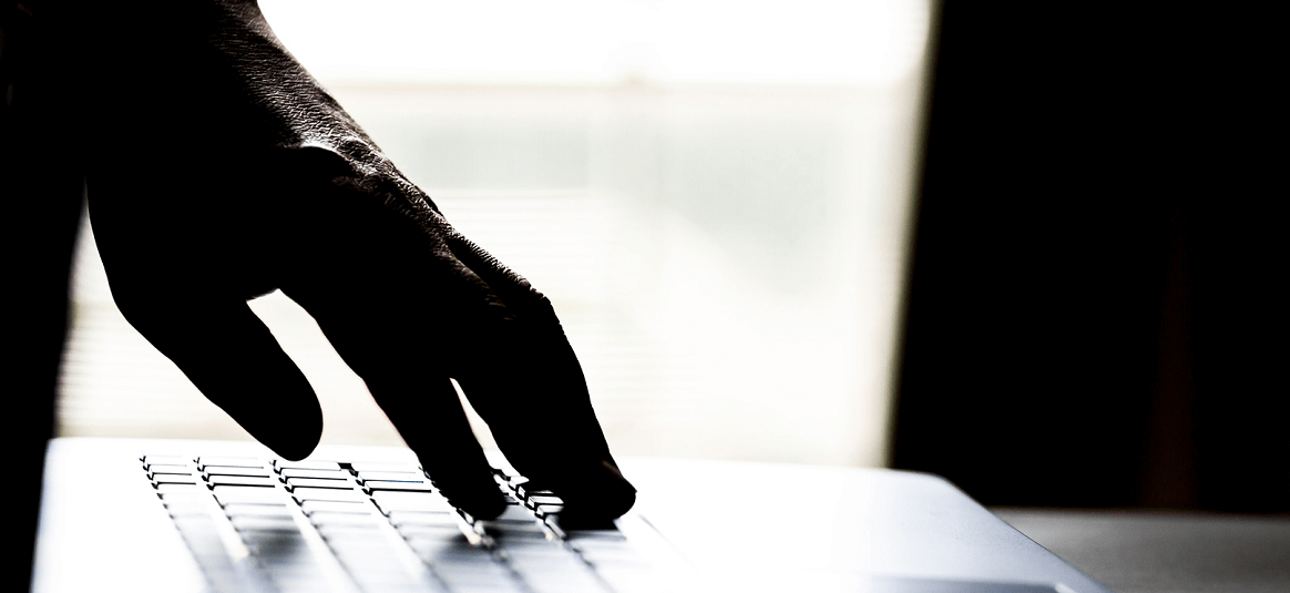 A silhouette of a hand on a laptop keyboard