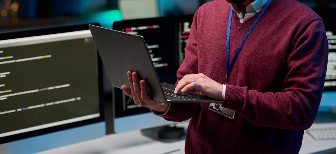 A person standing and using a laptop in an office