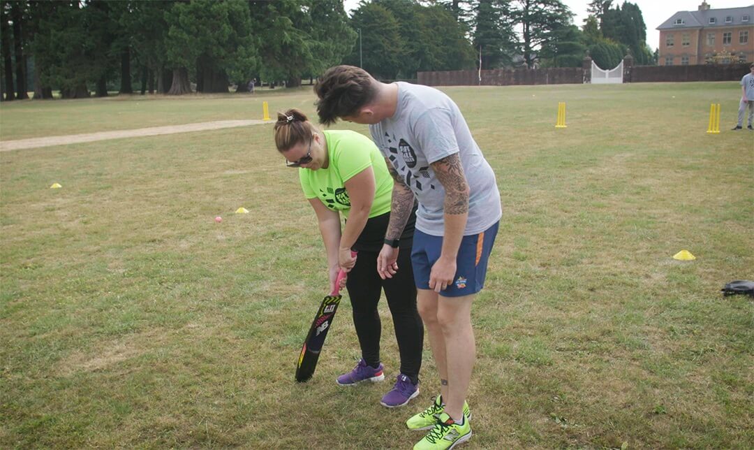 A man coaching a girl to play cricket