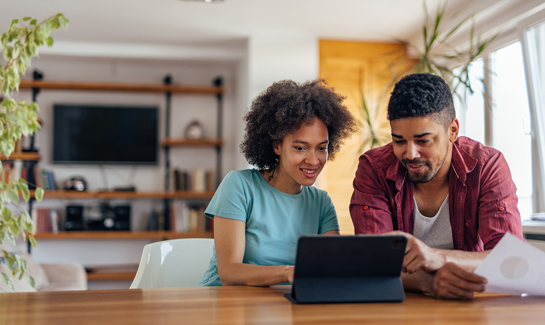 couple sitting at the table looking at digital tablet
