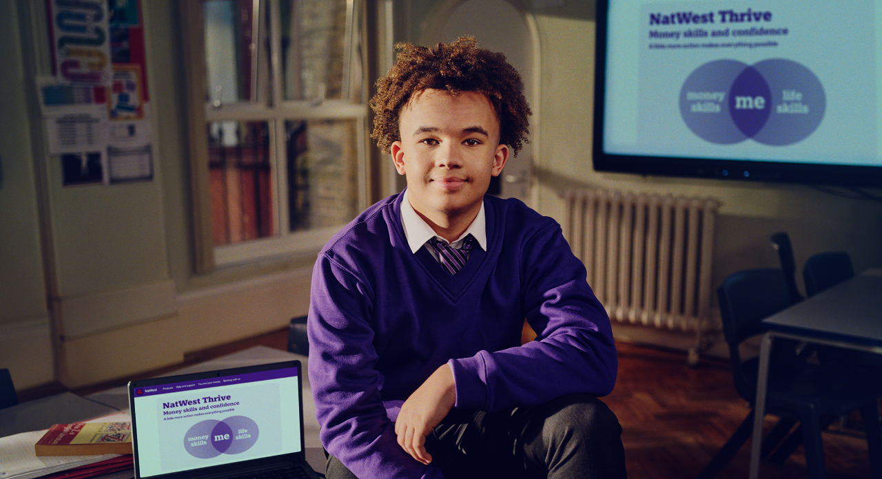 a boy with a laptop which says NatWest Thrive on the screen