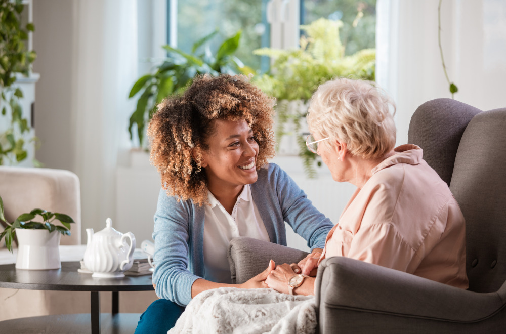 An older person sat in a chair being cared for by a young carer