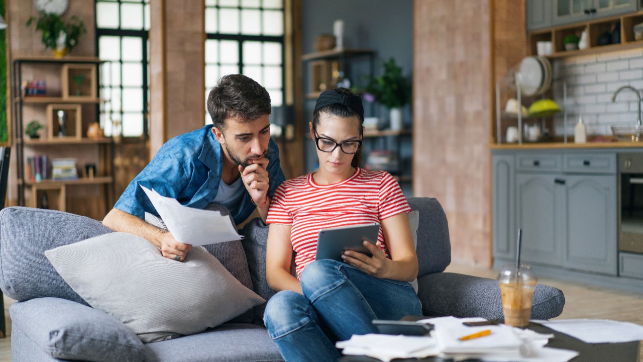Couple sitting on a couch calculating bills on an ipad