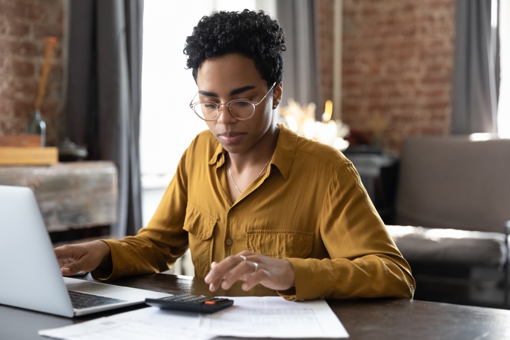 Woman sitting at her laptop trying to calculate her bills