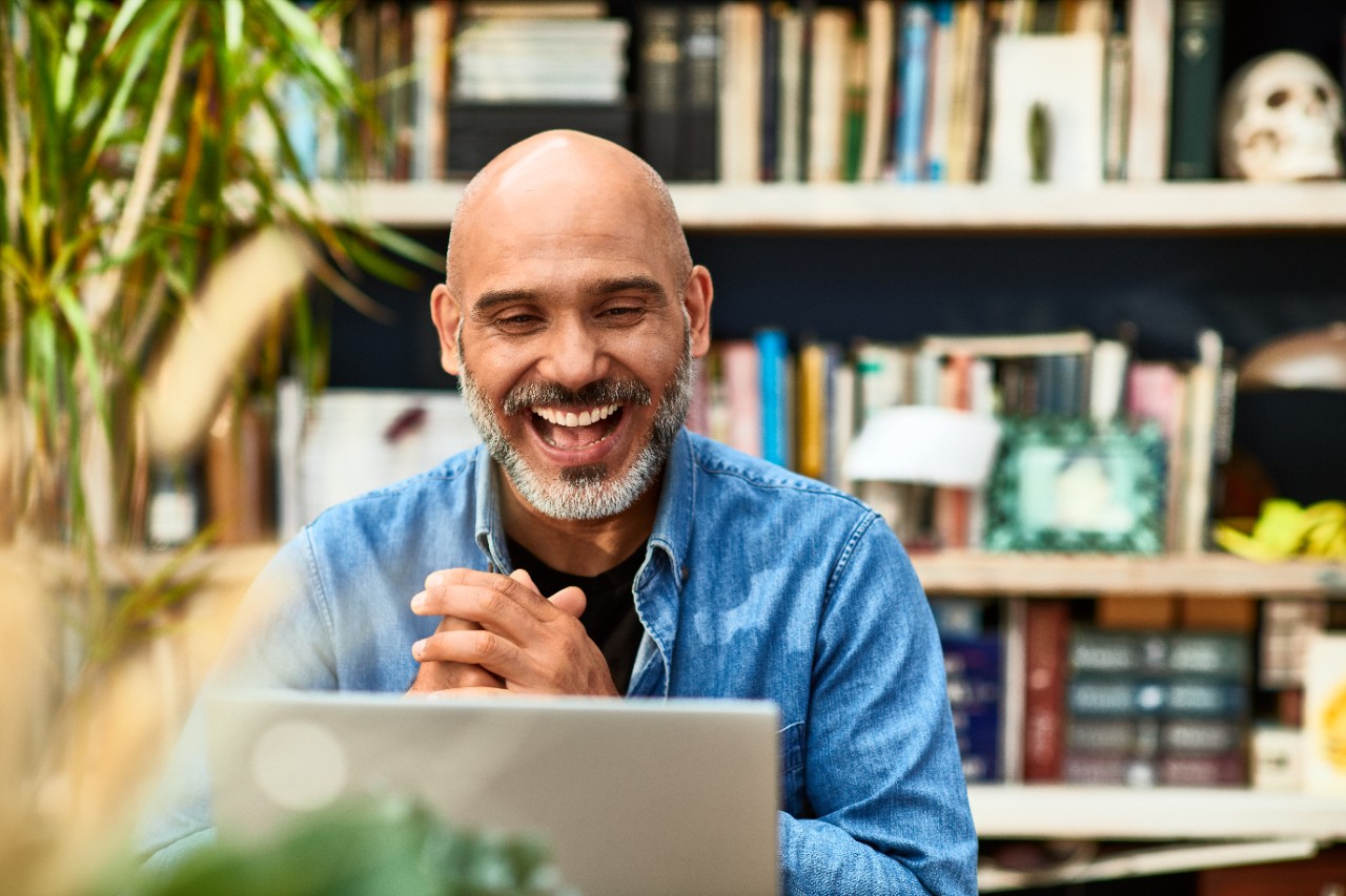 Man sitting at his desk on his laptop laughing